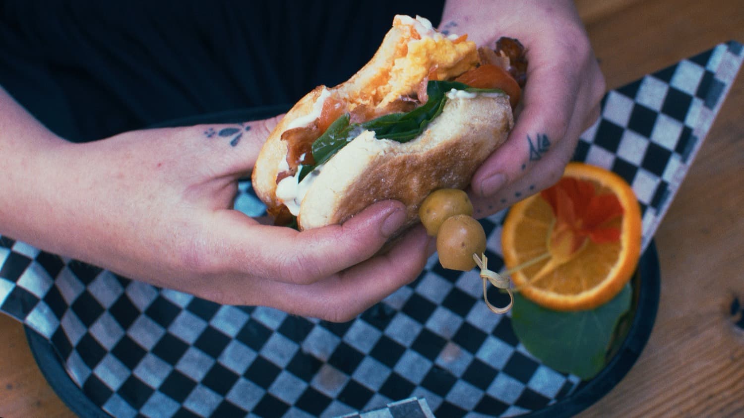 Hand holding a loaded breakfast sandwich